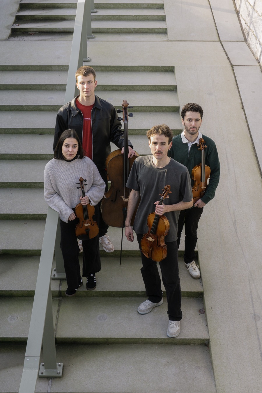 The four members of Luscofusco Quartet on outdoor concrete steps with their instruments