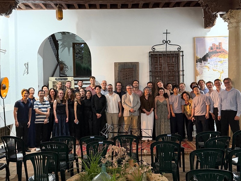 Group photo of the seminar’s musicians and teachers in a whitewashed courtyard, with rows of chairs in front